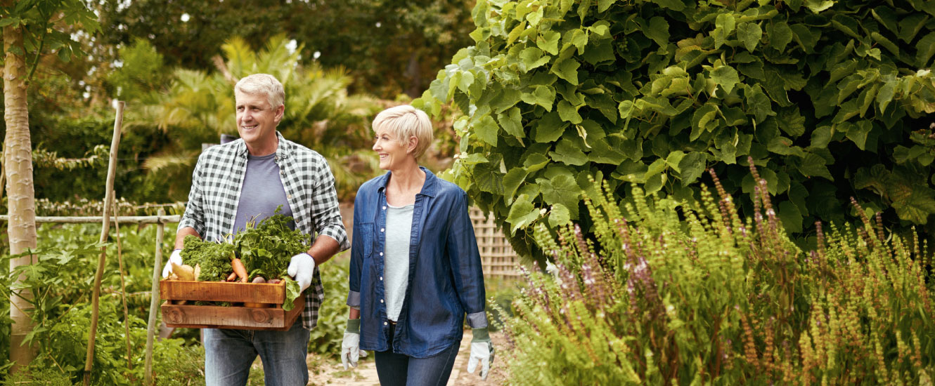 A mature couple walking through in a lush garden.